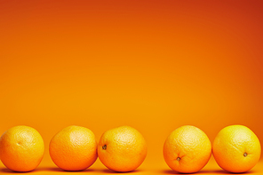 close-up view of fresh ripe oranges on orange background
