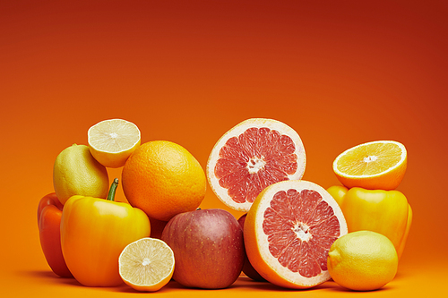 close-up view of fresh ripe citrus fruits and bell peppers on orange background