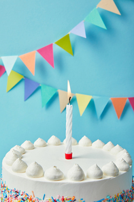 Candle on tasty birthday cake on blue background with bunting
