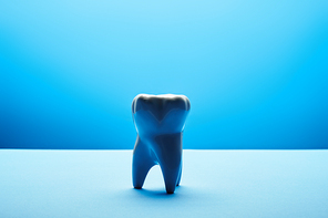 close up view of white tooth model on blue backdrop