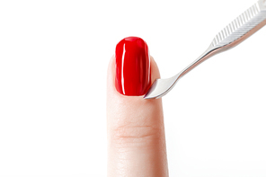 bright red nail polish on fingernail with cuticle pusher isolated on white
