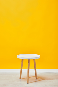 Minimalistic little wooden table near yellow wall