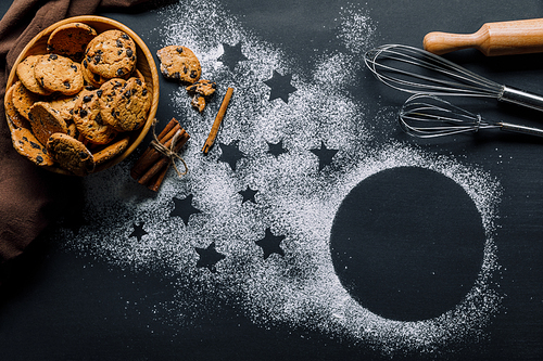 view from above of cookies in bowl| whisks and rolling pin on table covered by flour with symbol of stars