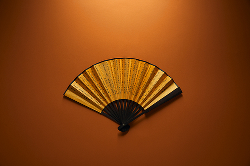 top view of decorative black and golden fan with hieroglyphs on brown background| chinese new year concept