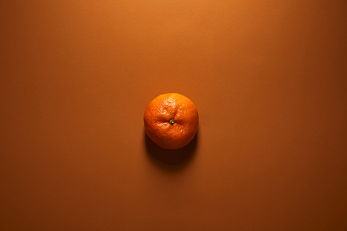 top view of whole single ripe tangerine on brown background