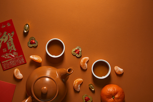 top view of tea set| tangerines and traditional chinese decorations on brown background