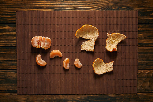 top view of peeled tangerine on bamboo mat on wooden table
