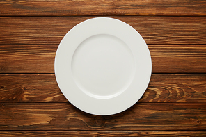 top view of white empty plate on wooden background
