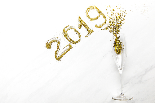 2019 numbers and champagne glass with golden confetti on white background