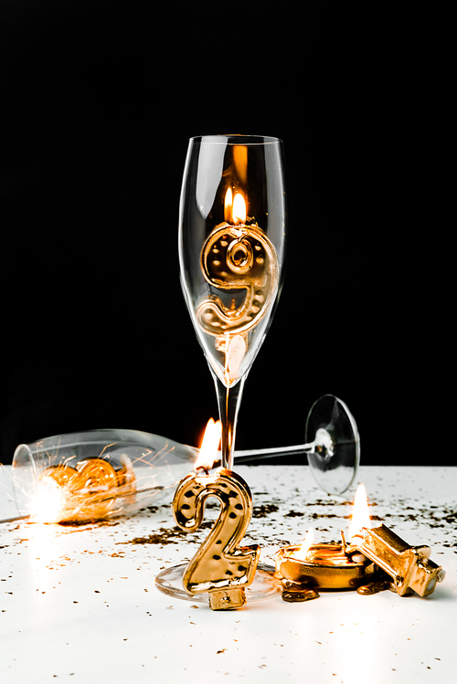 wine glasses and golden 2019 numbers with candles on black