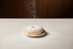 doughnut with icing and sprinkles with sifting sugar powder  on white table