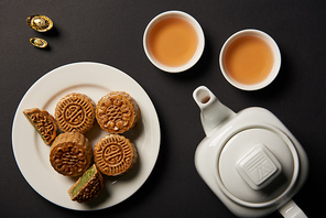 top view of mooncakes| cups and tea pot isolated on black