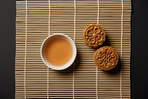 top view of chinese mooncakes and tea cup on bamboo table mat