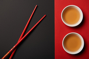 top view of chopsticks with traditional chinese tea on red and black background