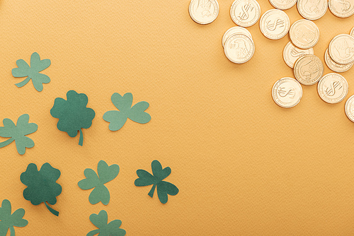 top view of golden coins with dollar signs| shamrocks and copy space isolated on orange| st patrick day concept