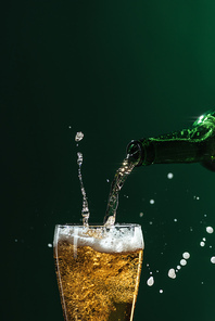 pouring beer into glass with splashes and copy space isolated on green| st patrick day concept