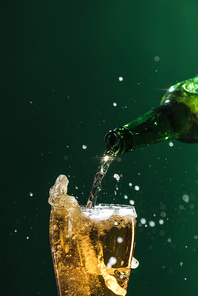 pouring beer into glass with splashes and copy space isolated on green| st patrick day concept