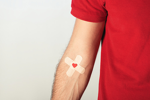 Partial view of patient in red t-shirt with plasters on grey background| blood donation concept