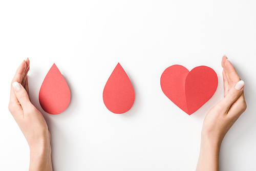 Partial view of woman holding paper heart and drops on white background