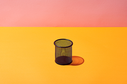 empty pencil holder on yellow surface and pink background