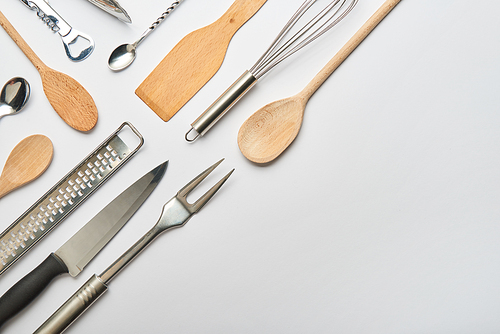 flat lay with metal and wooden cooking utensils on grey background