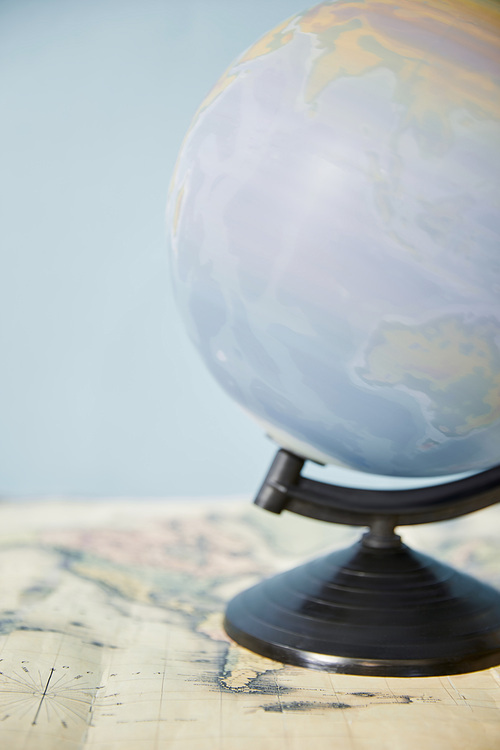 Selective focus of spinning globe and map isolated on blue