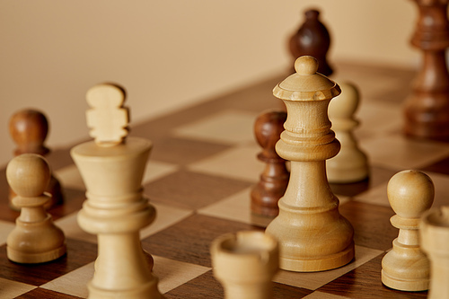 selective focus of wooden chess pieces on chess board and beige background