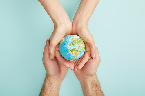 top view of man and woman holding planet model on turquoise background| earth day concept