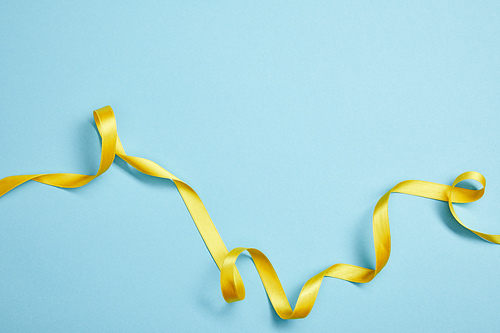 top view of yellow satin ribbon on blue background