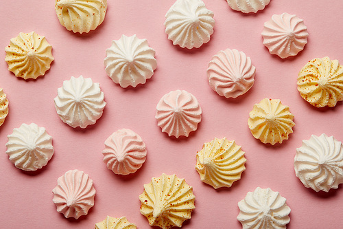 Flat lay with white, pink and yellow meringues on pink background