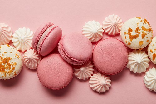 Pink and white tasty macaroons with pink and white meringues on pink background