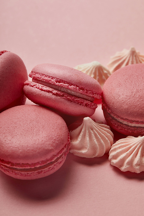 Pink macaroons with small meringues on pink background