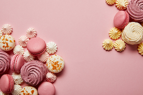Delicious sweet macaroons and colorful meringues on pink background