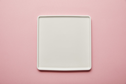 Top view of white square flat plate on pink background