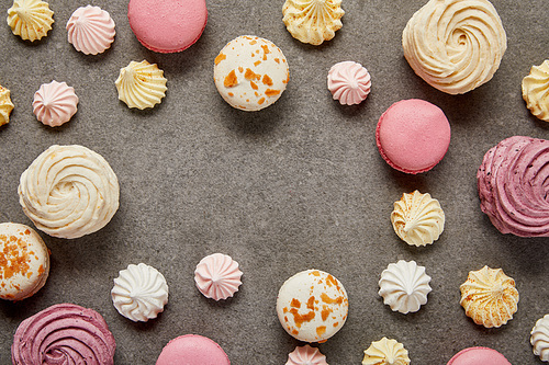 Top view of pink and white macaroons with meringues on gray background