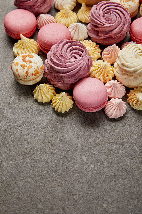Tasty assorted small meringues, soft zephyr with french macaroons on gray background