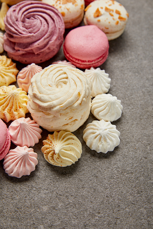 Delicious assorted soft zephyr, small meringues and macaroons on gray background