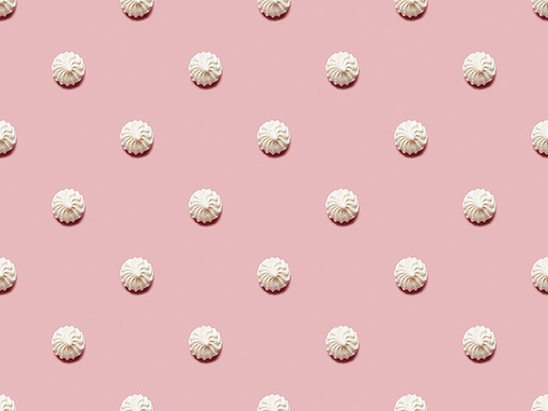 Flat lay with small white meringues on pink background