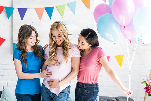 multicultural friends and pregnant woman touching belly at baby-party