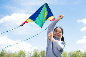 low angle view of smiling child holding kite in park