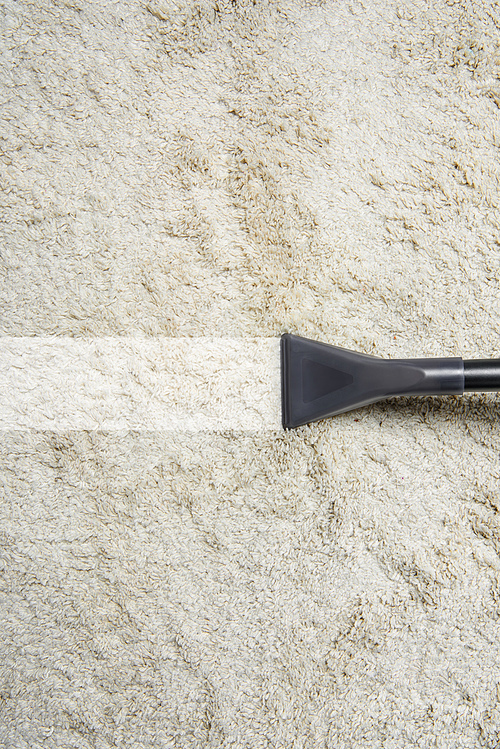 close-up view of cleaning white carpet with professional vacuum cleaner