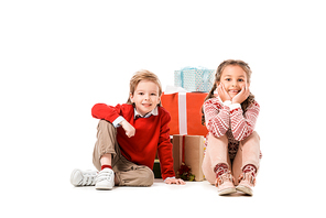 adorable little kids sitting on floor with pile of christmas gifts isolated on white