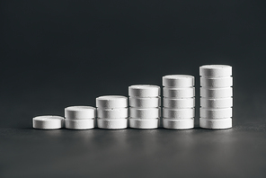 close up view of arranged stacks of white pills placed in rows on grey