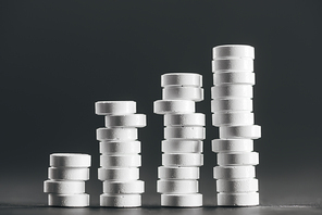 close up view of arranged stacks of white pills placed in rows on grey
