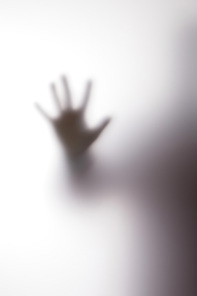 Blurry silhouette of person touching glass with hand