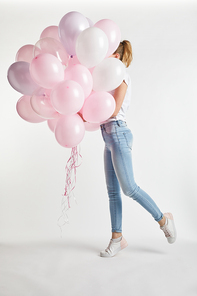 girl in casual clothes covering face with pink air balloons on white