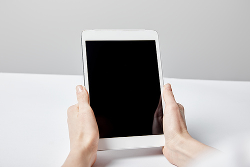 cropped view of woman holding digital tablet with blank screen on grey