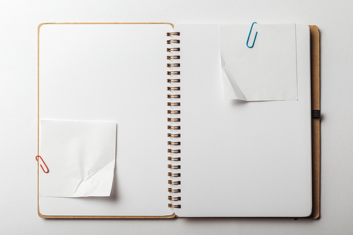 top view of notebook with sticky notes and paper clips on white background