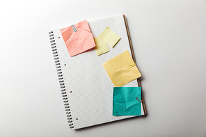 top view of notebook with blank squared page near crumpled sticky notes on white background