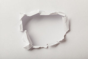 torn hole in sheet of paper on white background
